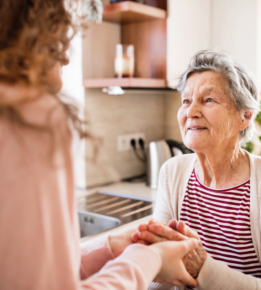 Seniorin wird von einer Angehörigen im eigenen Zuhause unterstützt